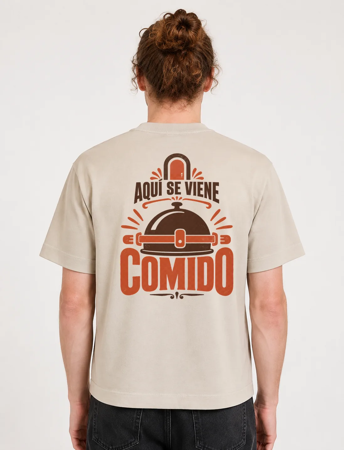 Espalda de una camiseta Cream oversized con el diseño «Aquí Se Viene Comido»: una campana de servicio con rayos alrededor