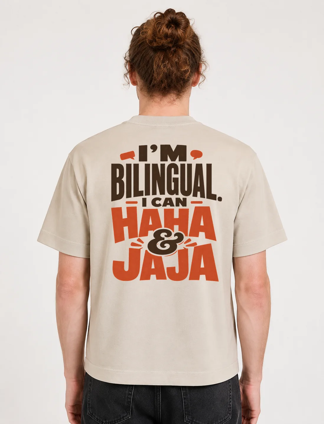 Espalda de una camiseta Cream oversized con el diseño «I'm Bilingual. I Can Haha & Jaja»: letras en bloque con «haha» y «jaja» resaltados en terracota