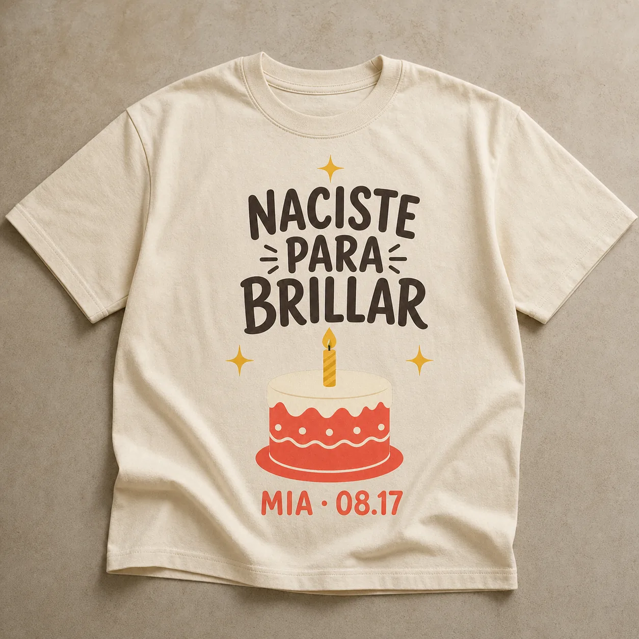 Camiseta Cream con el estampado «Naciste Para Brillar»: una tarta roja con una vela encendida, y un nombre y una fecha de ejemplo debajo.
