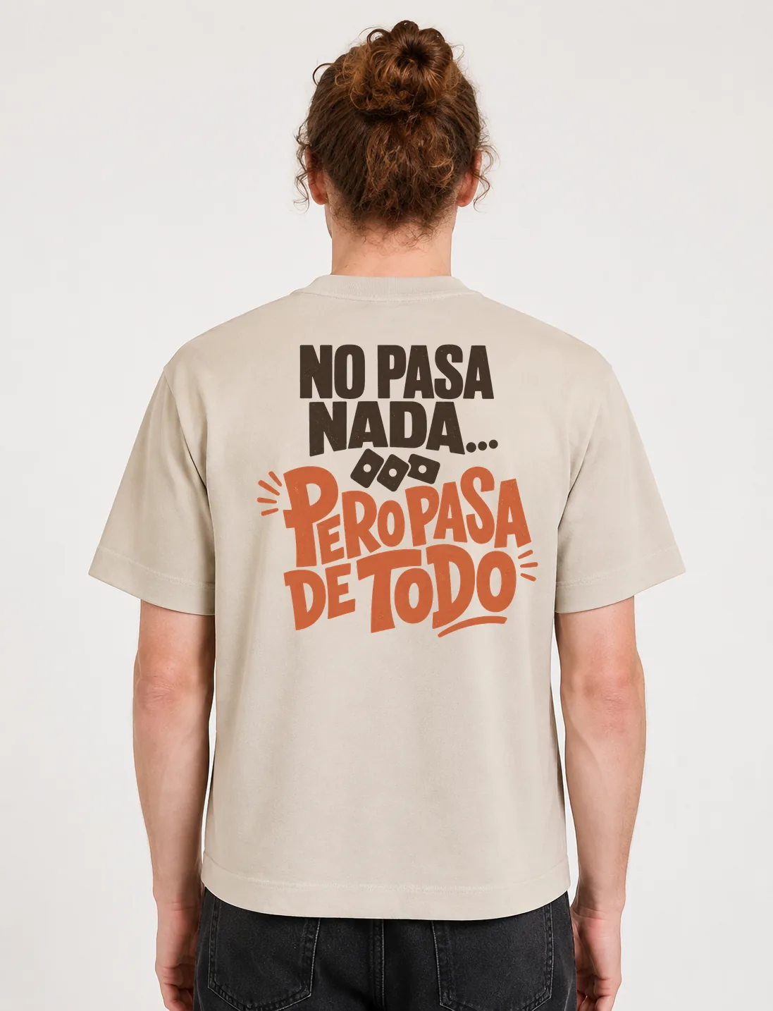Espalda de una camiseta Cream oversized con el diseño «No Pasa Nada… Pero Pasa de Todo»: dos bloques de letras separados por tres cuadritos a modo de puntos suspensivos